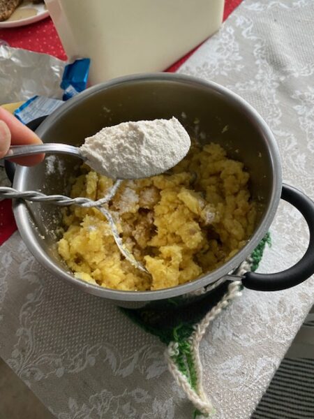 Kattilassa oleva perunasurvos, johon lisätään lusikallinen vehnäjauhoja imellettyä perunalaatikkoa varten.